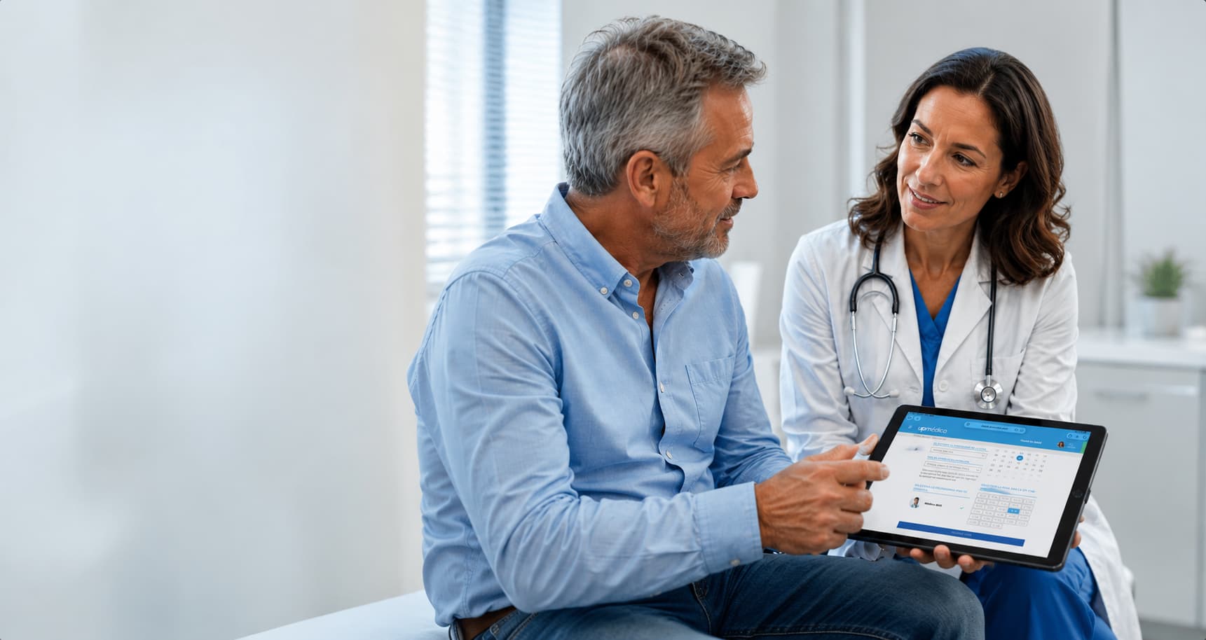 Médica y paciente conversando en consulta mientras revisan información clínica en una tablet con Upmédica.